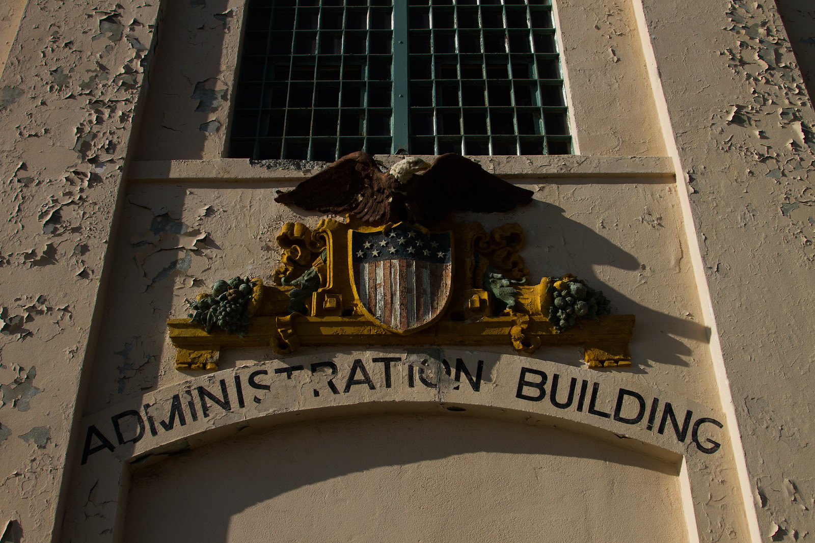 Weathered facade with a painted eagle-and-shield crest above an arched doorway reading "Administration Building.