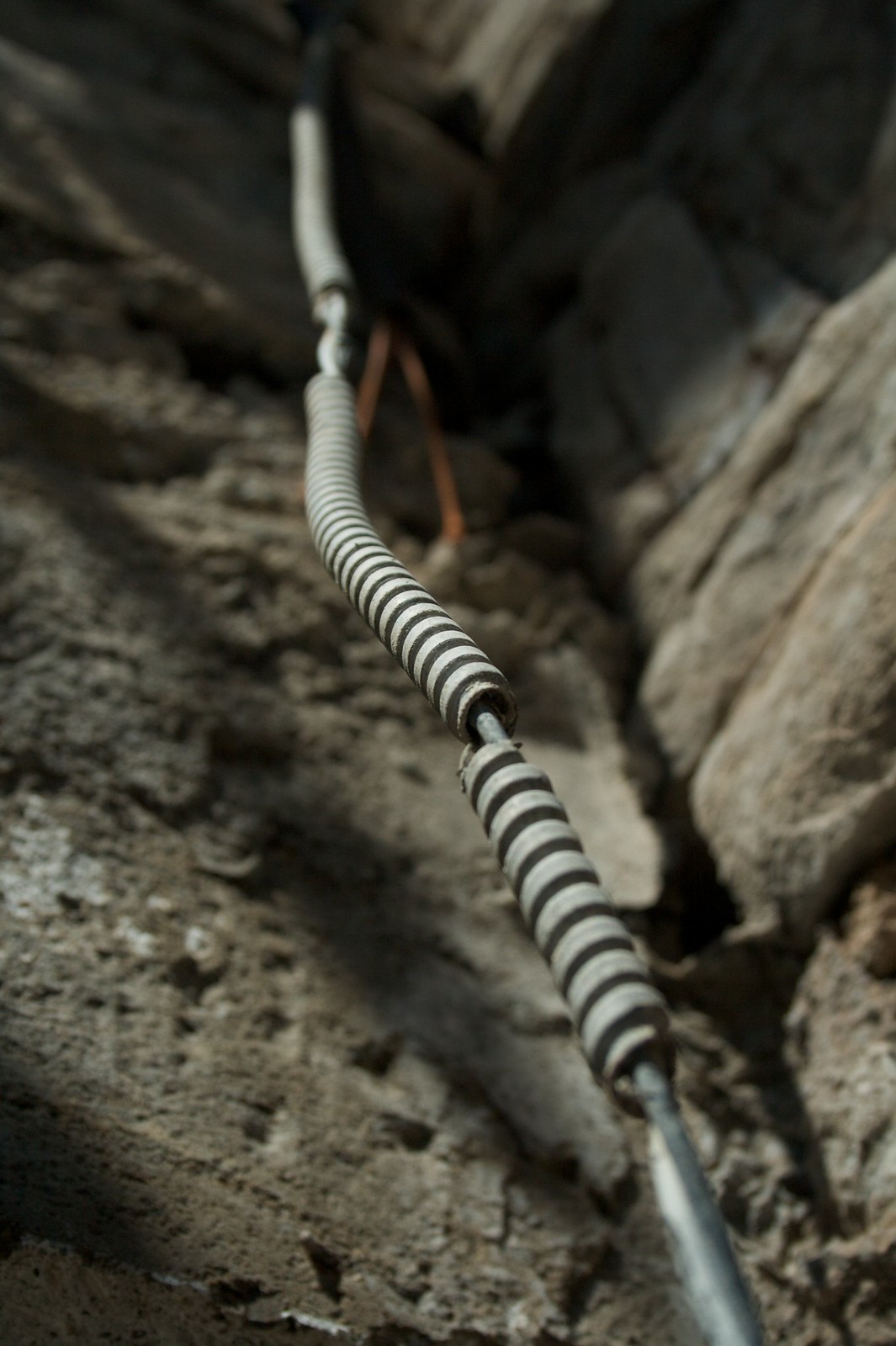 Coiled black-and-white wire springs stretched taut across weathered gray rock and metal stakes.