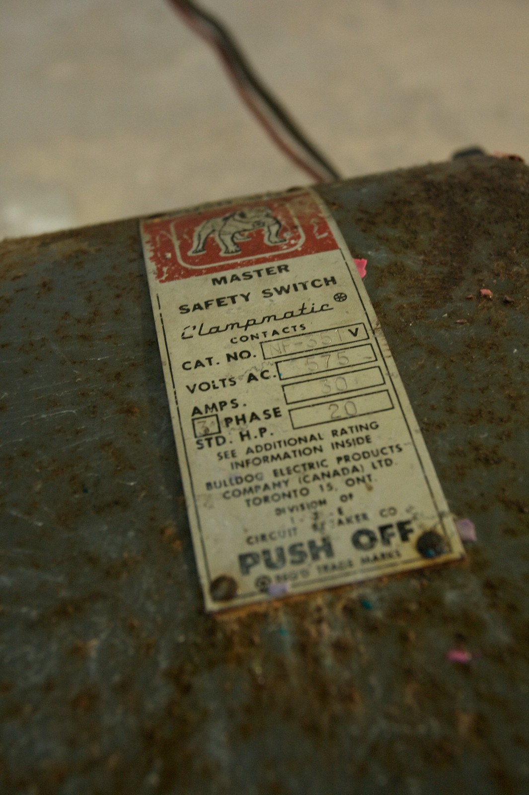Worn Bulldog Electric "Master Safety Switch" nameplate with bulldog logo on a rusty box, reading "PUSH OFF.