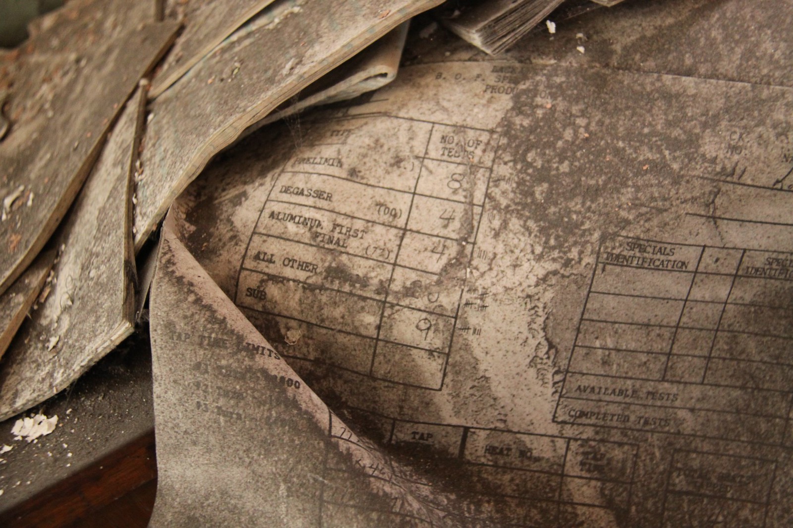 Dust-covered abandoned steel-mill ledger showing a "No. of Tests" table with rows like Degasser and Aluminum First Final.
