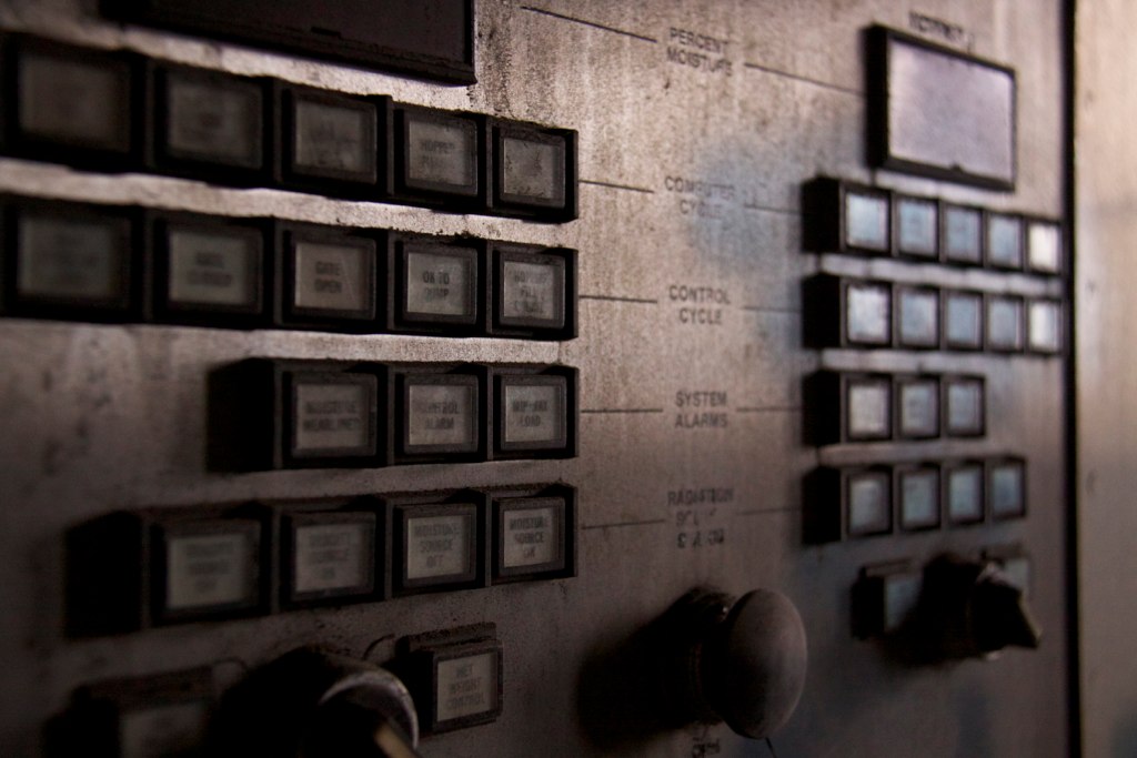 Dusty industrial control panel with rows of illuminated buttons labeled "Computer Cycle," "Control Cycle," and "System Alarms.