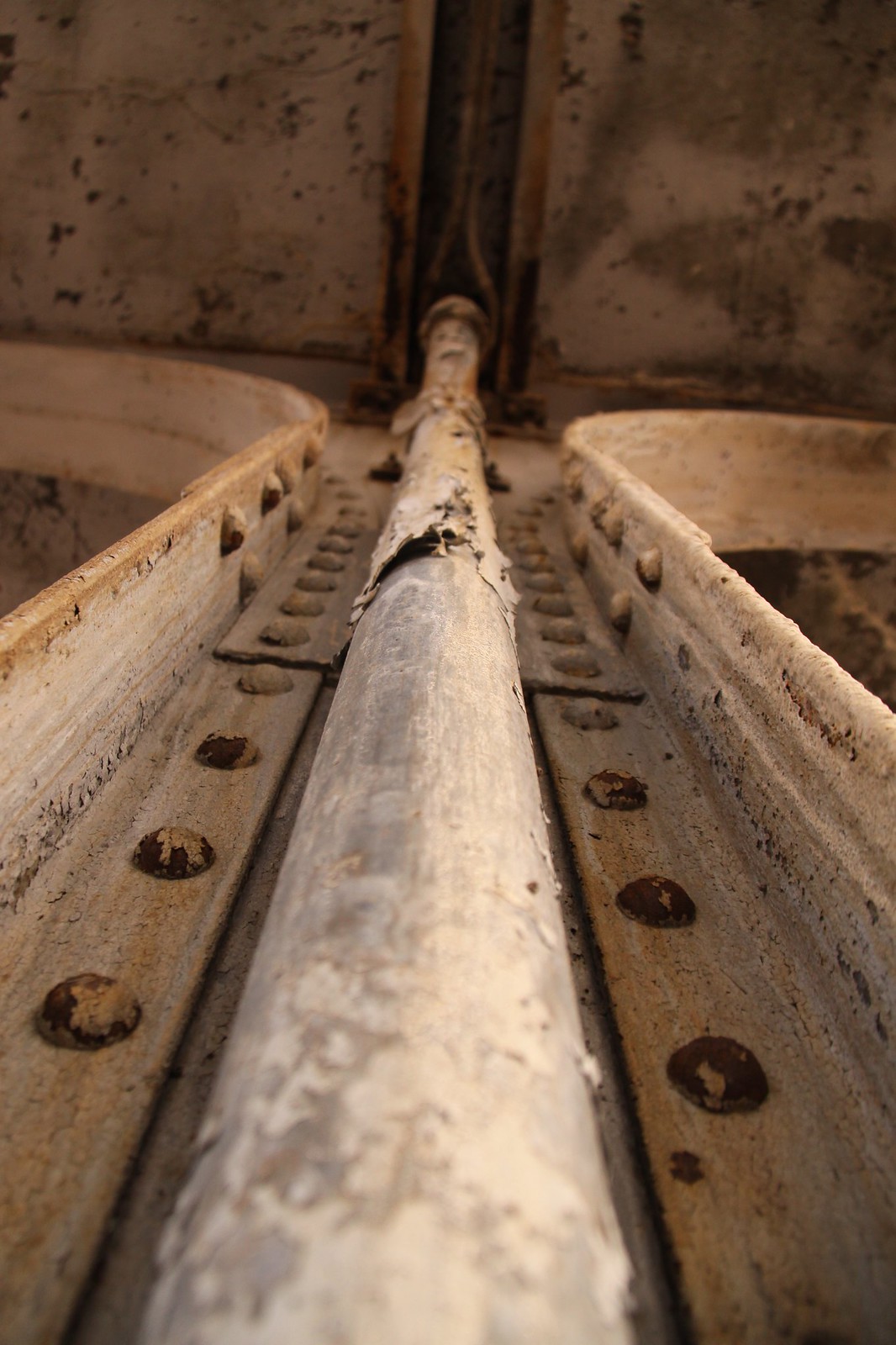 Weathered, paint-peeling metal pipe running along a riveted seam in the derelict Buffalo Central Terminal.
