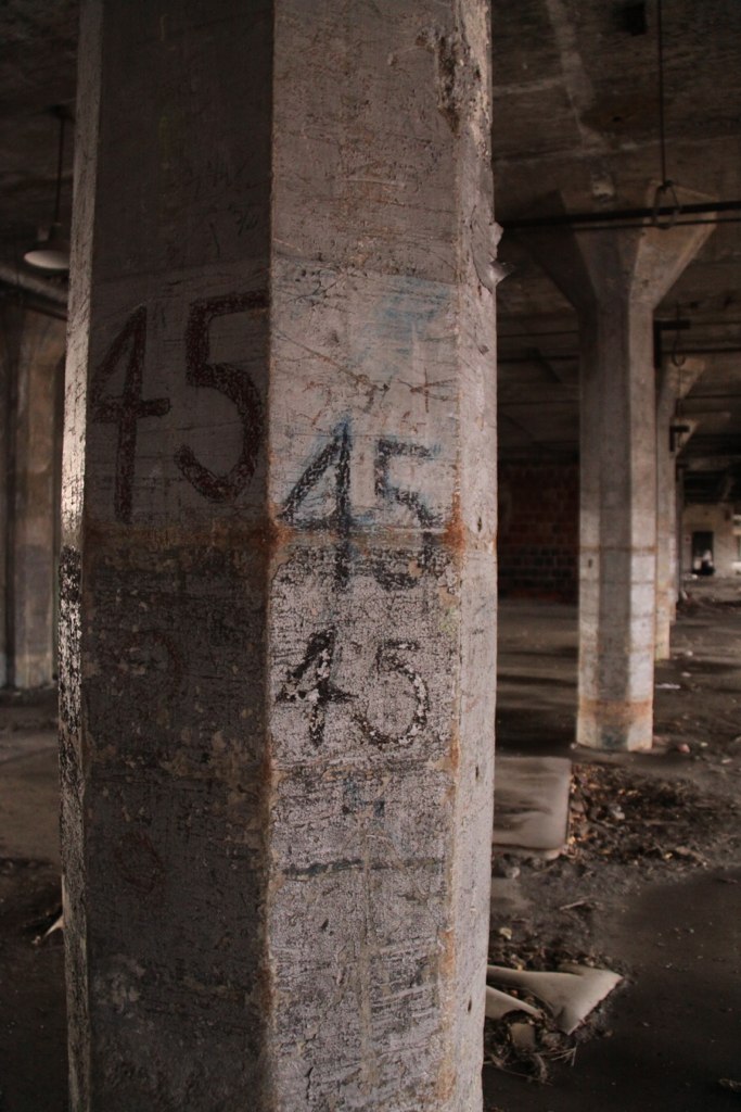 Concrete support pillars marked with hand-painted "45" numbers inside a dim, derelict Buffalo Central Terminal hall.