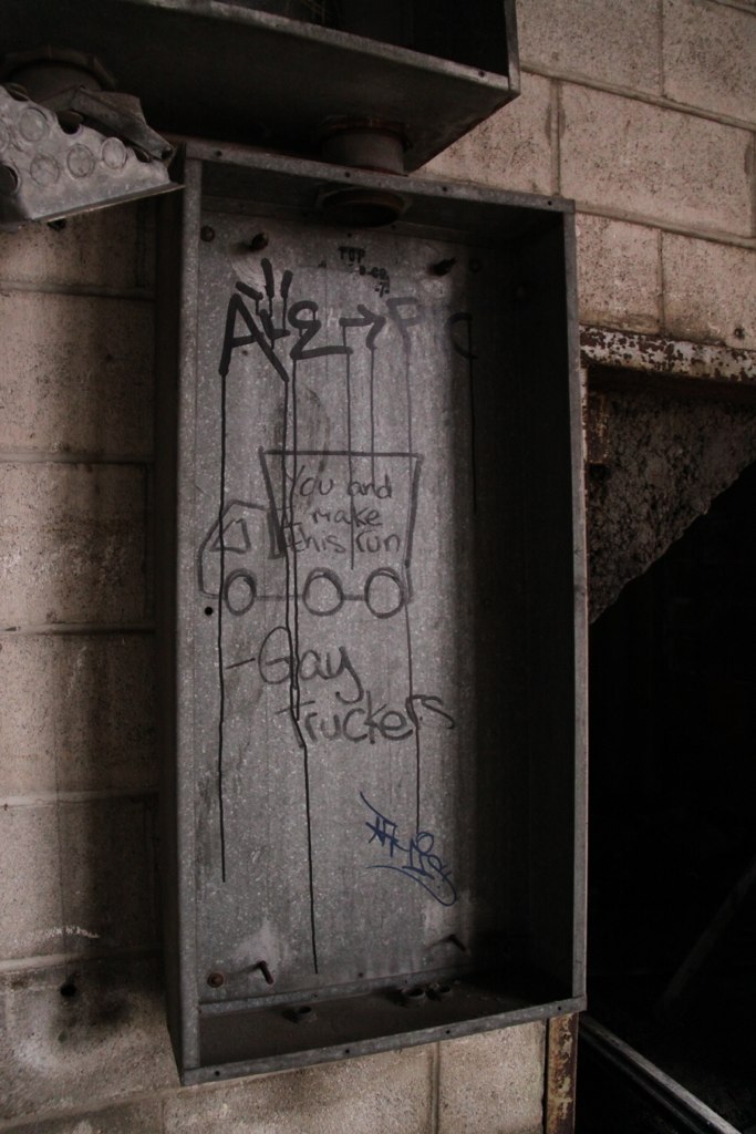 Hand-drawn graffiti of a truck on a metal box labeled "You and me make this run — Gay Truckers" in a derelict building.