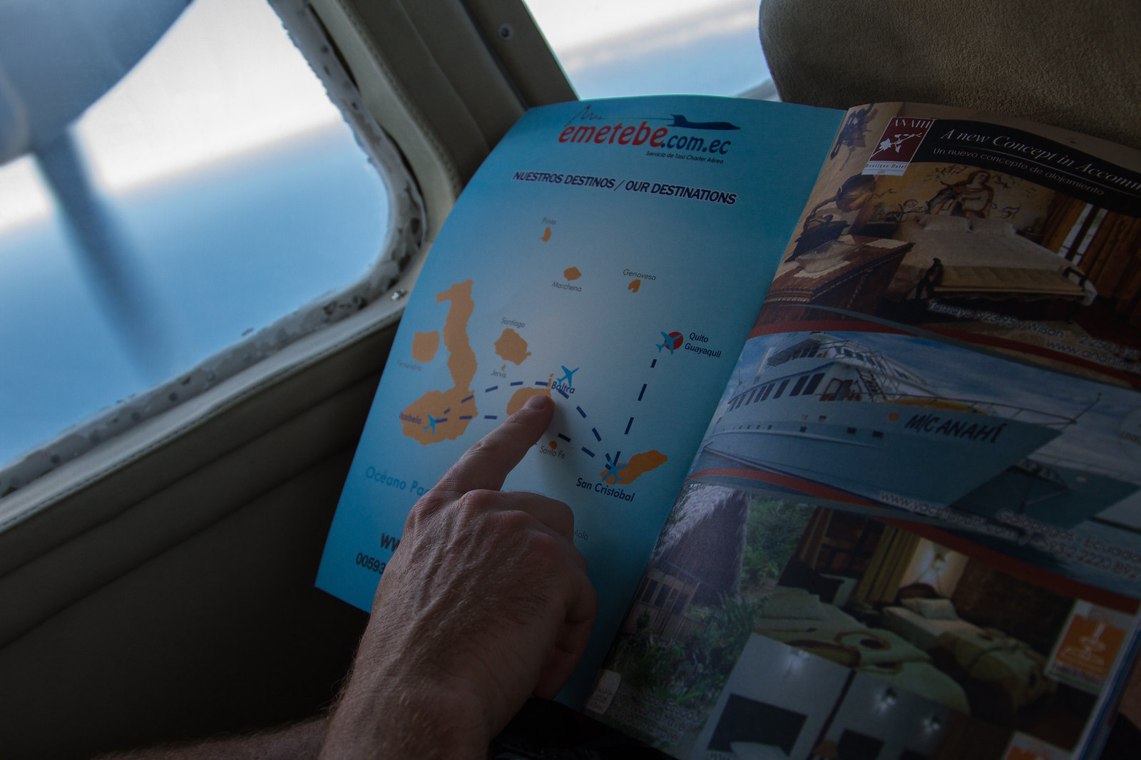 A hand points to Baltra on a map of Galápagos destinations in an emetebe.com.ec charter flight brochure.