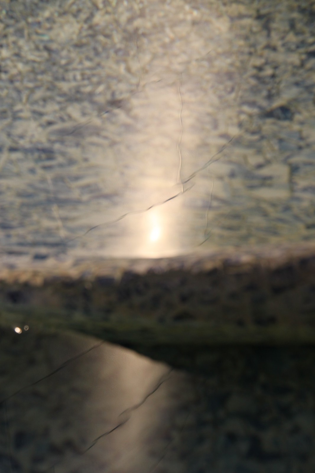 Blurred golden light reflected in the rippling stainless steel surface of a Gehry building's curved wall.