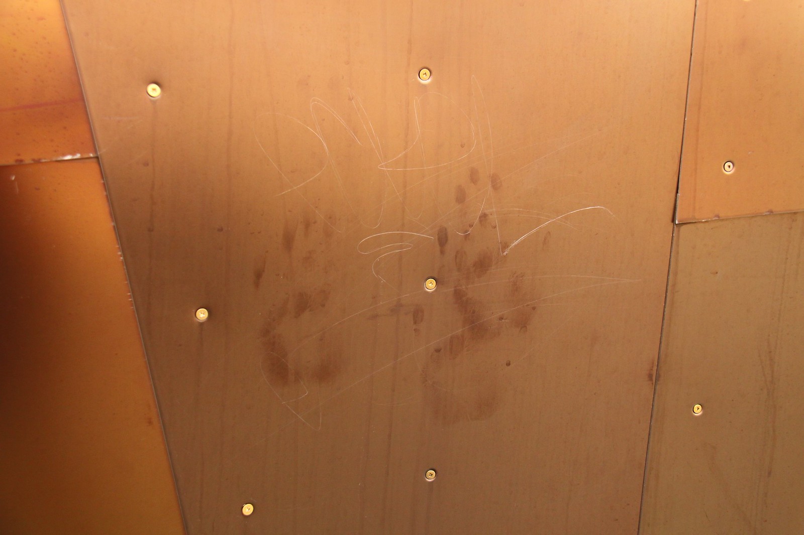 Bolted metal skin panels marked with handprint smudges and scratched graffiti.