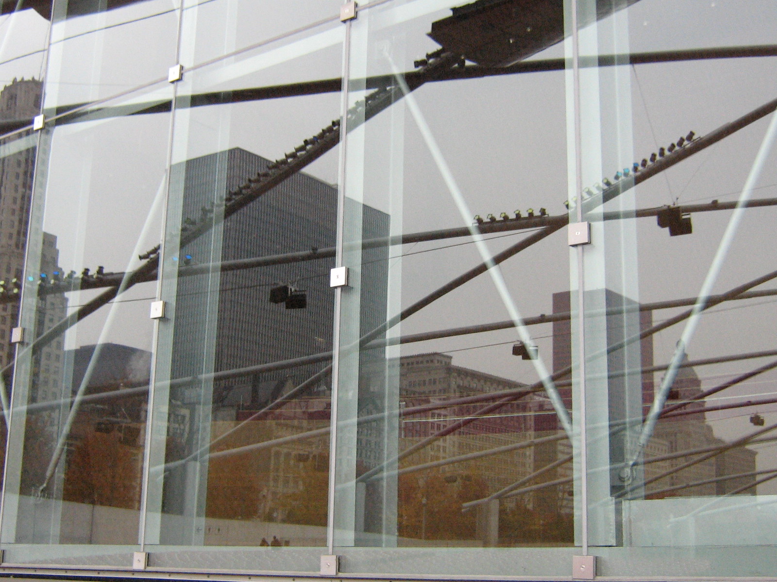 Chicago skyscrapers reflected in the glass wall and steel trusses of Millennium Park's Pritzker Pavilion.