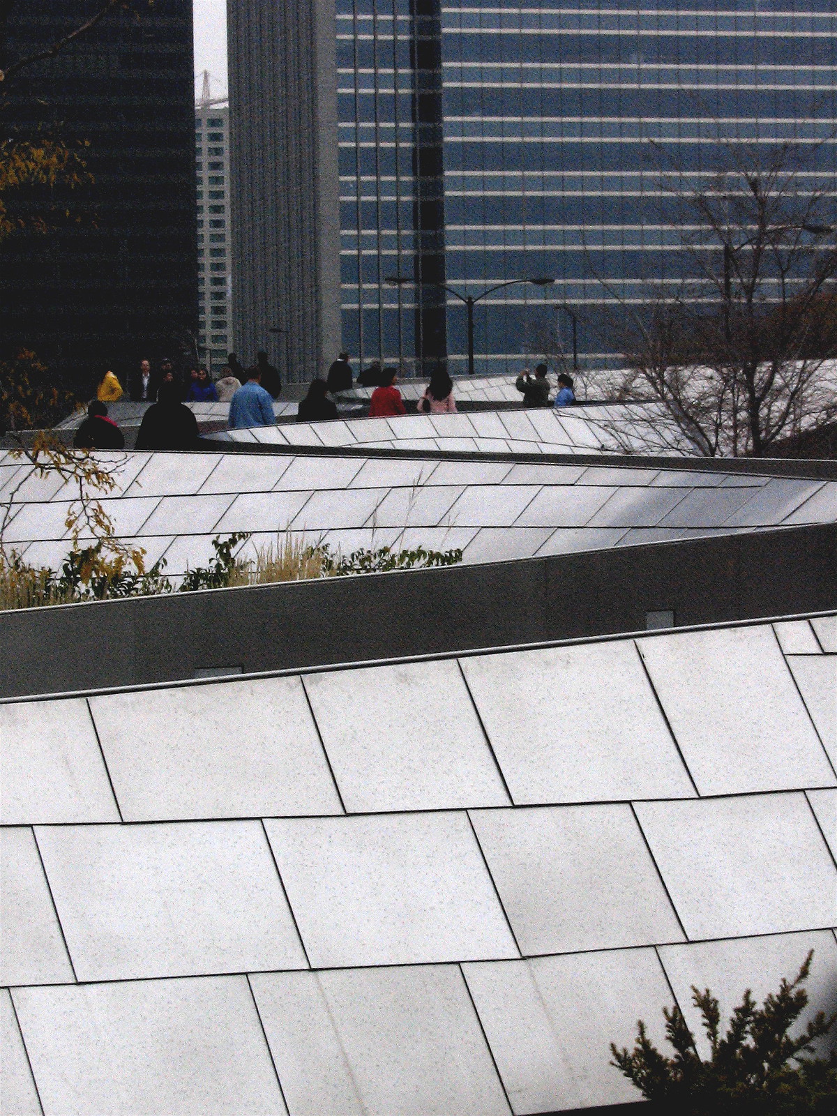 People walk along Gehry's curving BP Bridge in Millennium Park below Chicago skyscrapers