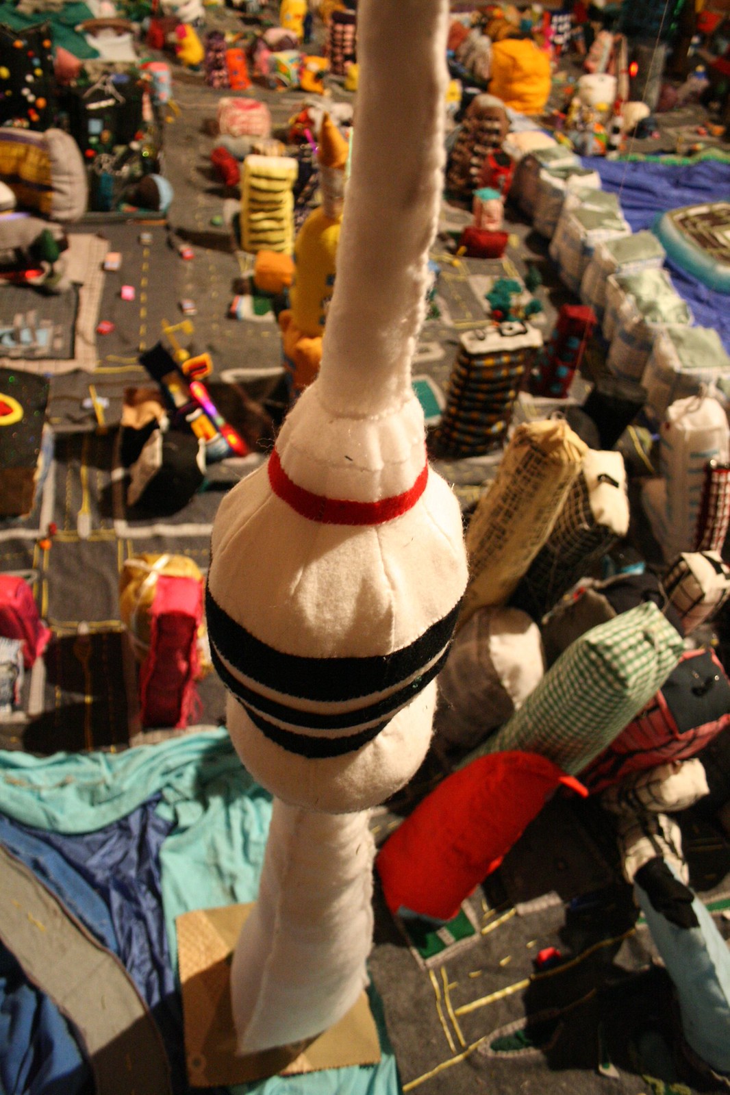 A soft-fabric miniature city with a plush communications tower rising above stitched buildings and streets.