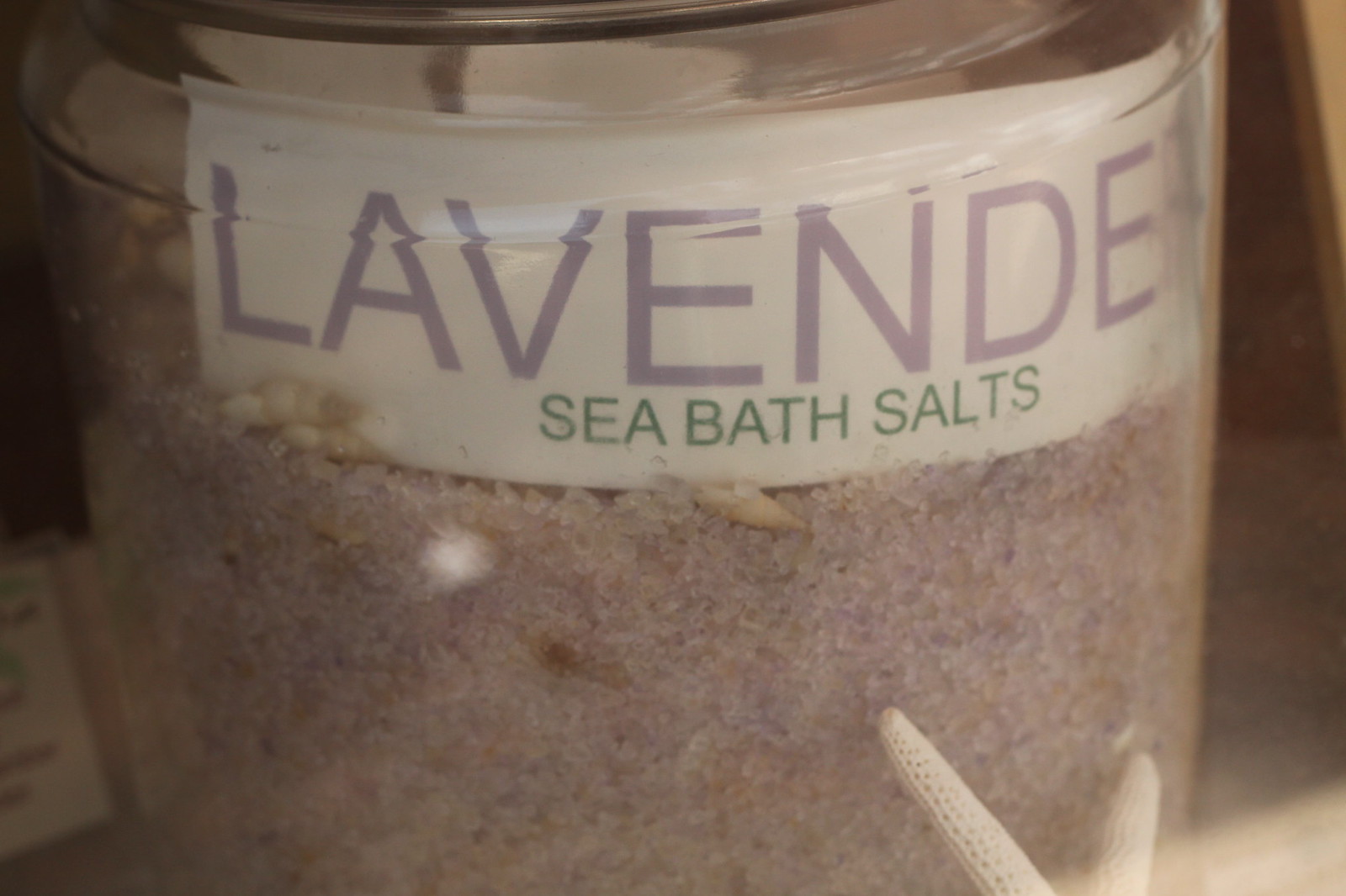 Close-up of a glass jar labeled "Lavender Sea Bath Salts" with a starfish inside.