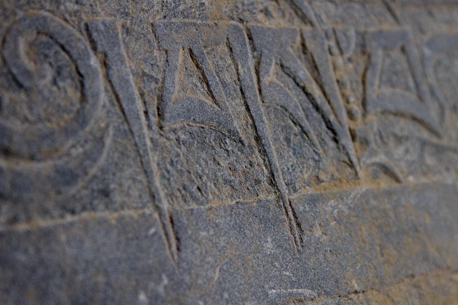 Close-up of Tibetan script carved into a weathered grey stone mani slab