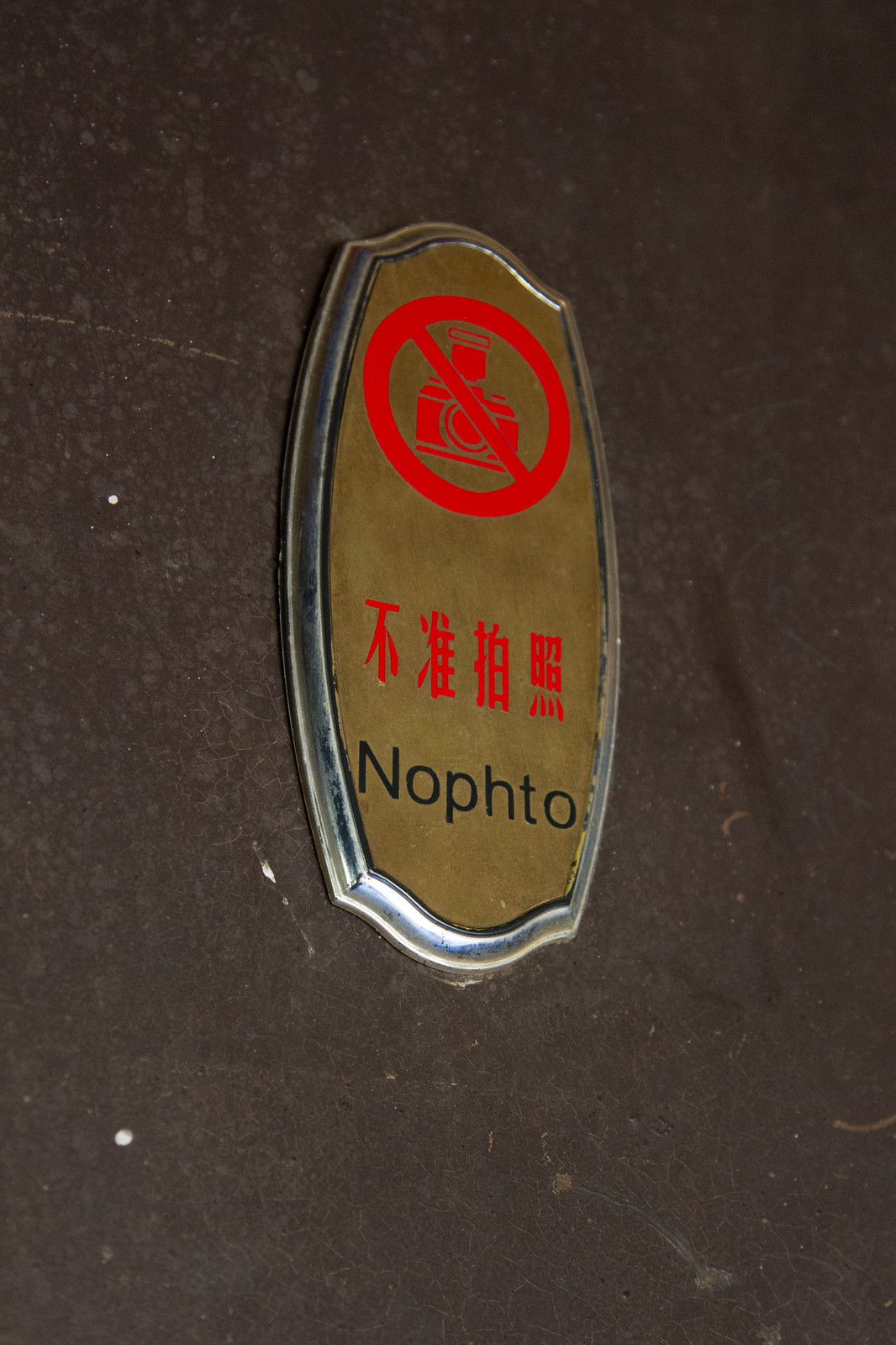 Brass no-photography plaque with a red crossed-out camera, Chinese "不准拍照," and misspelled "Nophto.