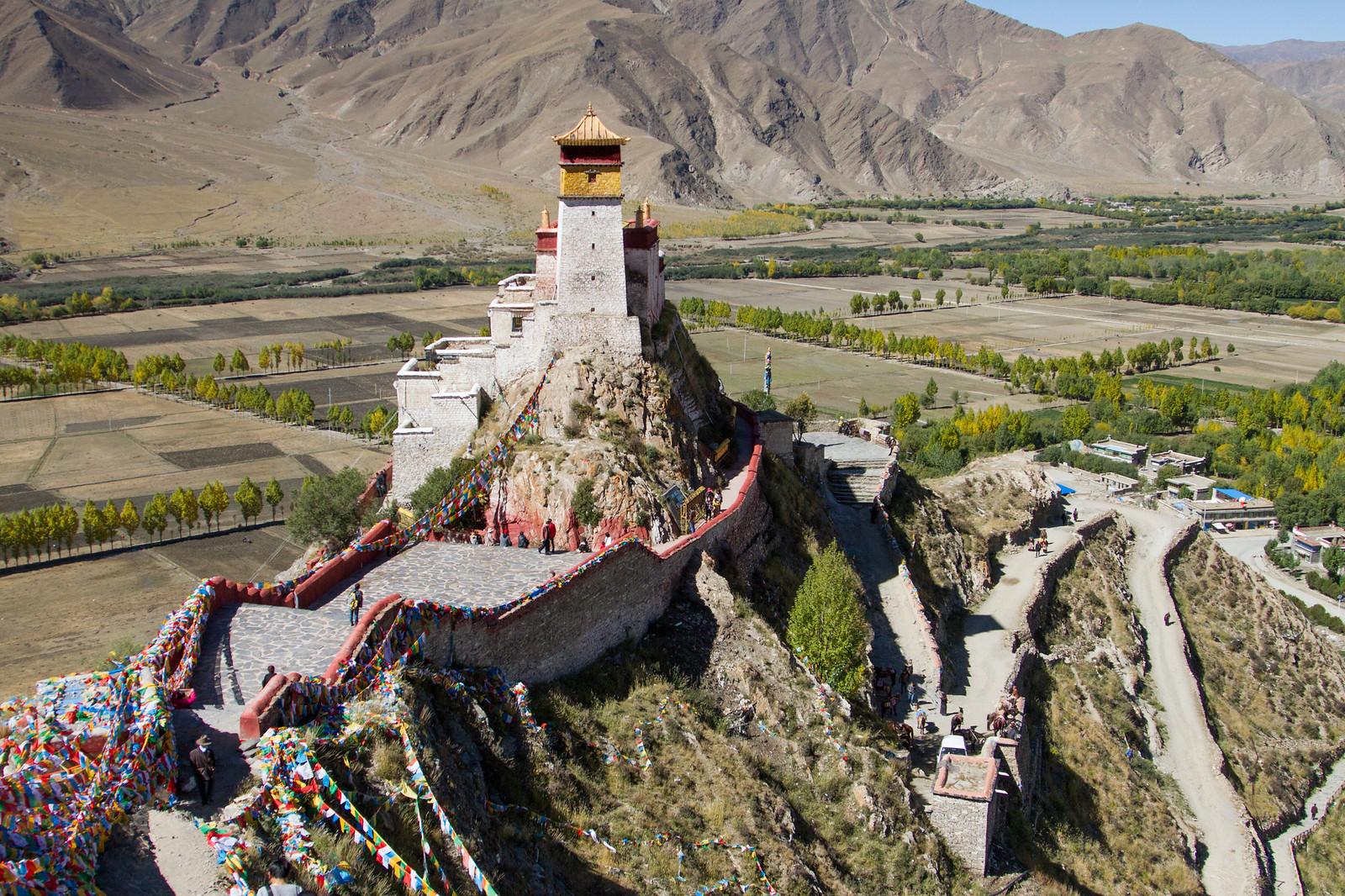 Yumbulagang palace on a ridge above the Yarlung Valley, draped in colorful prayer flags.